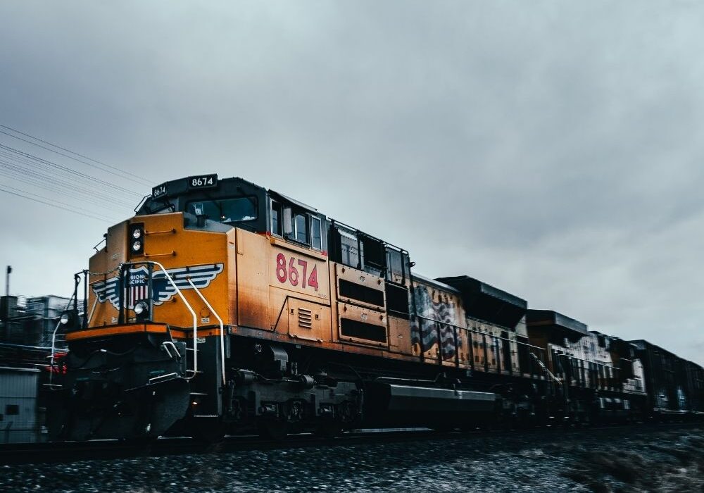 A moody, slightly dark image of an orange and dark gray diesel locomotive on the tracks.