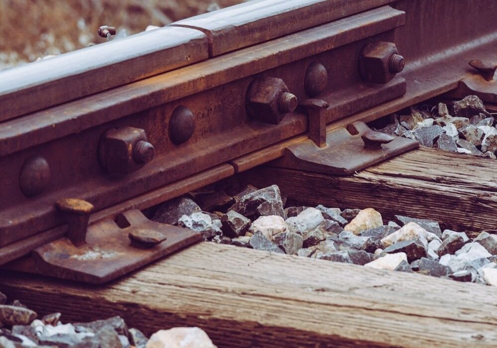 A close-up of a bolted rail joint on a wooden tie.